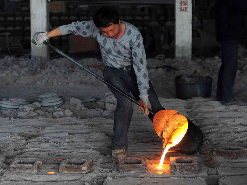 A Chinese worker pours molten steel into A Chinese worker pours molten steel into